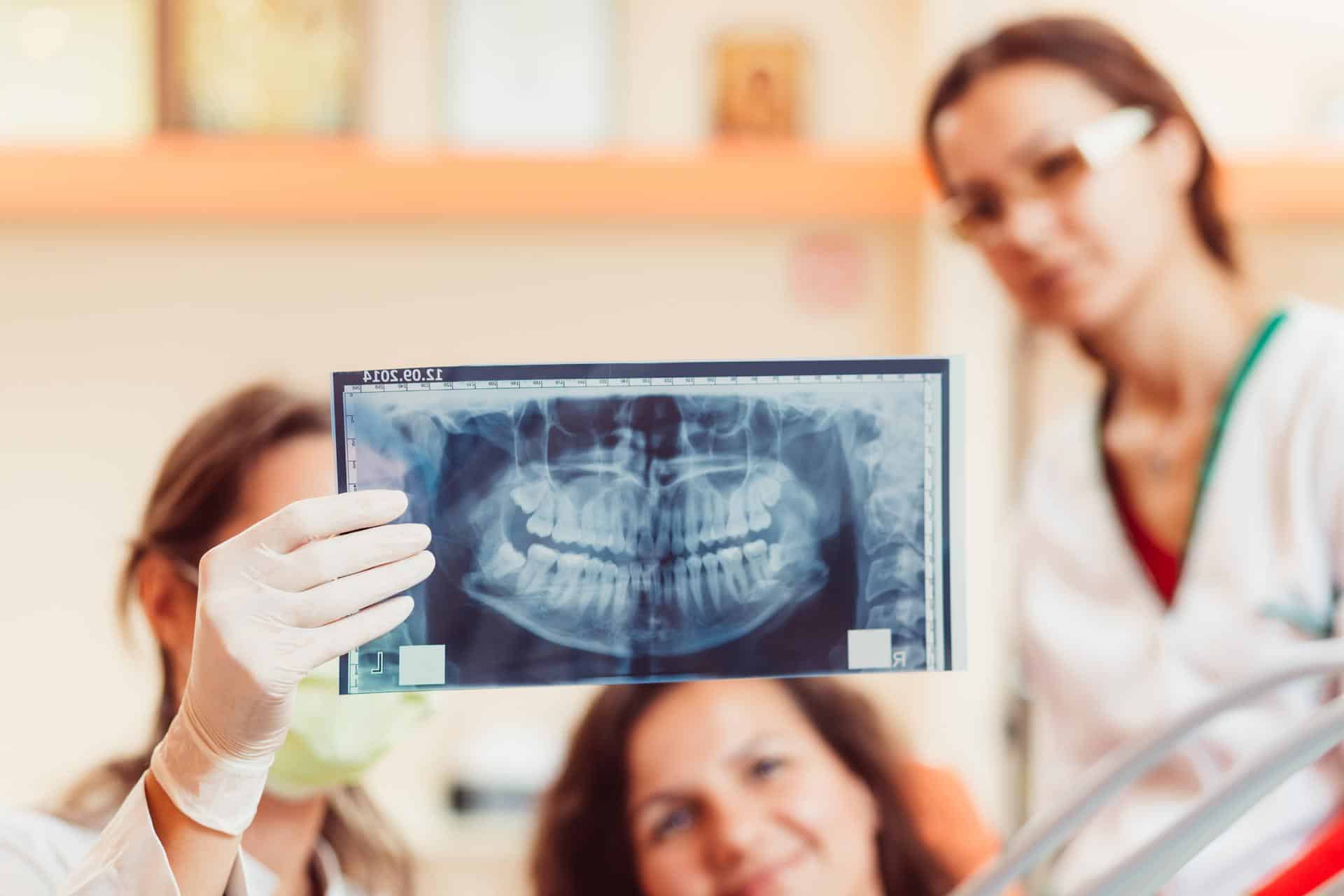 Dentistas e paciente observam exame para diagnóstico odontológico