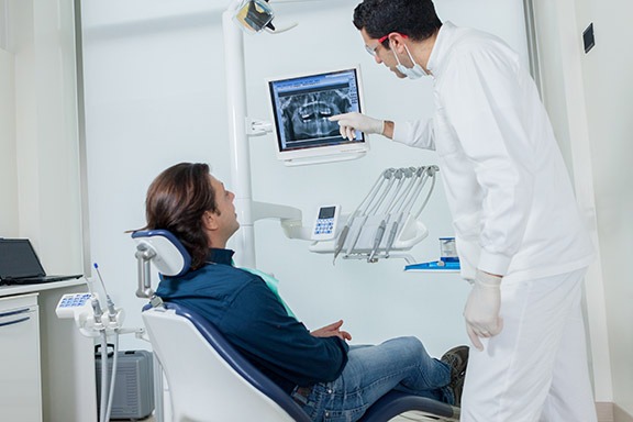 dentista aponta imagem de radiologia odontológica digital para paciente sentado na cadeira