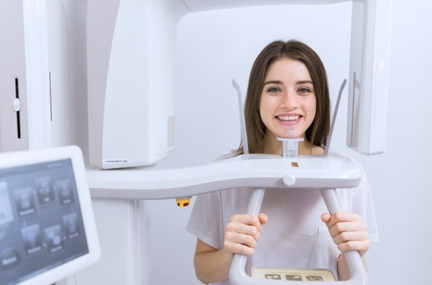 mulher sorri em máquina de radiologia odontológica digital